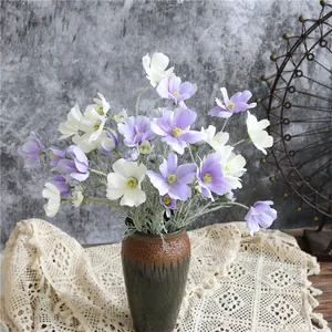 Vista dettagliata di fiori di cosmo artificiali viola e bianchi in un vaso rustico