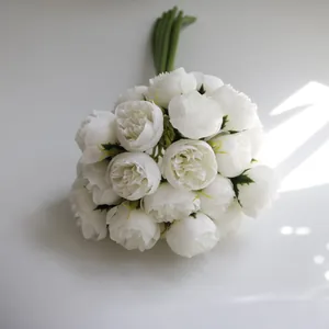 Close-up of a 27-head white silk tea rose bouquet with natural window light shadows.