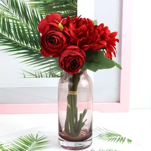 Detailed view of elegant red artificial silk roses and gerberas in a pink glass vase