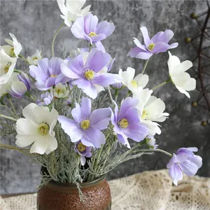 Vista dettagliata di fiori di cosmo artificiali viola e bianchi in un vaso rustico.