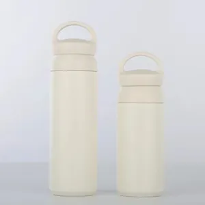 Vue détaillée de deux bouteilles isothermes minimalistes de couleur crème avec poignées