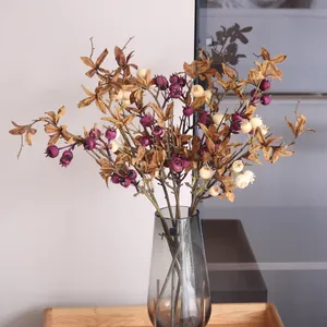 Detailed shot of artificial berry branches with purple fruits in a sleek grey glass vase