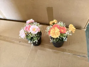 Detail view showing two colorful artificial daisy flower potted plants in small black plastic pots