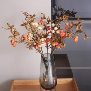Close-up of decorative artificial pomegranate and tomato fruit branches in a vase