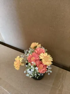 Detailed top view of artificial pink and yellow daisy potted plant ornament
