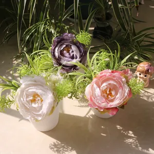 Detail of three artificial peony pots in white, pink, and purple under sunlight