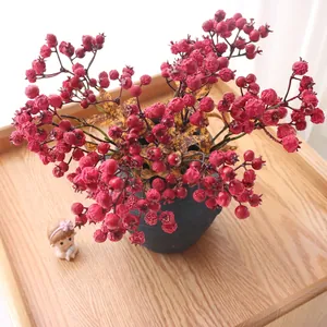 Close-up view of realistic artificial red berries in a dark textured ceramic vase for decor