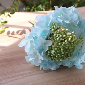Close-up of light blue silk hydrangea flower head with green berries for home decor.