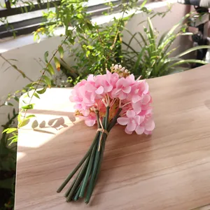 Close-up of pink silk hydrangea bouquet on a wooden table with natural lighting