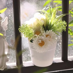 Detail of artificial white daisy and yellow peony flowers in a minimalist white pot.