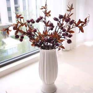 Close-up of artificial berry branches in a white fluted ceramic vase for home decor