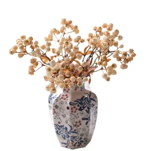 Elegant artificial berry stems in a decorative blue and red floral ceramic vase