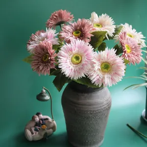 Close-up of realistic pink artificial Gerbera daisies in a textured grey ceramic vase.