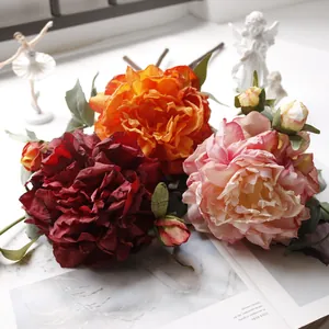 Detailed macro view of high-quality artificial silk peonies in red, orange, and pink colors.