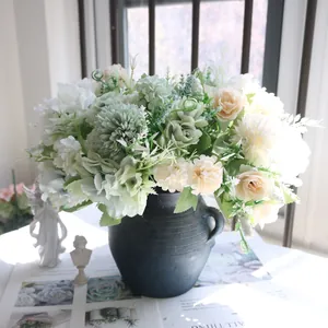 Vue détaillée d'un bouquet de roses artificielles et de boules d'oignons dans un vase bleu.
