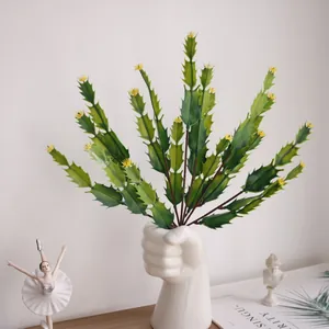 Realistic artificial cactus branch with yellow flower buds in a creative white fist vase