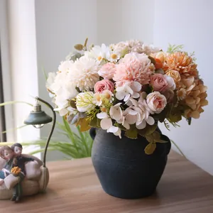 Nahaufnahme eines herbstlichen Kunstblumenarrangements mit Rosen und Chrysanthemen in einer Vase