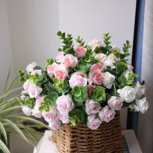 Detail view of realistic pink and white silk roses with eucalyptus leaves in a woven basket