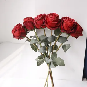 Detaillierte Nahaufnahme eines künstlichen Straußes mit 6 roten Rosen und gebrannten Kanten.