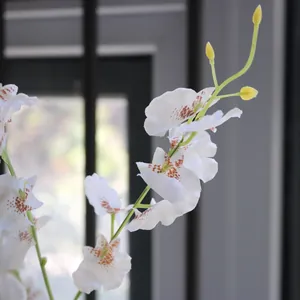 Close-up detail of artificial white dancing orchid silk flower with brown spots.