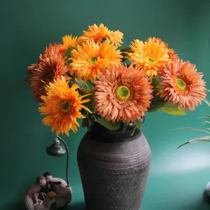 Detailed view of vibrant orange artificial gerbera daisies in a vintage vase