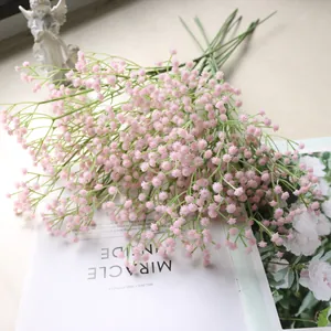 Nahaufnahme von rosa künstlichen Schleierkrautblüten auf einem weißen Buch.