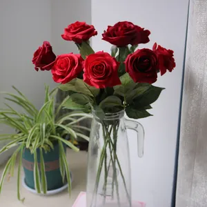 Beautiful deep red artificial silk roses arranged in a clear glass pitcher for home decor