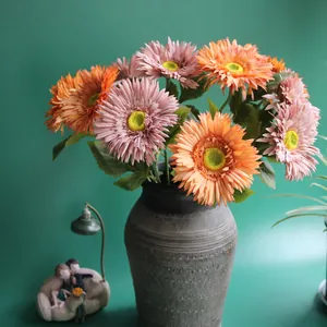 Detail shot of realistic pink and orange artificial Gerbera daisies in a vintage vase