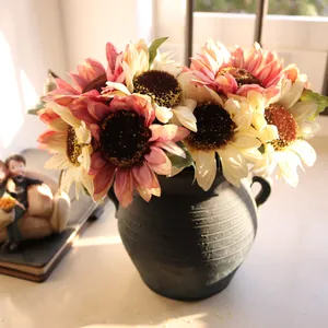 Detailed view of artificial pink and cream sunflowers in a rustic dark vase.