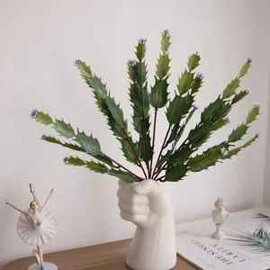 Detail view of artificial cactus plant inside a creative fist shaped white ceramic vase.