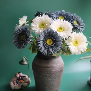 Close-up of white and blue artificial Gerbera Daisies in a grey textured vase