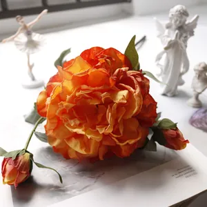 Detailed close-up of vibrant orange silk peony with delicate buds in a luxury setting