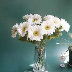 Detailed view of white artificial gerbera daisy flowers in a gold-rimmed glass vase