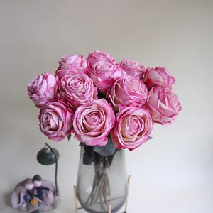Detaillierte Nahaufnahme rosa künstlicher Rosen mit gebrannten Kanten in einer Vase.