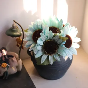 Detailed view of light blue artificial sunflowers in a rustic black vase for decor