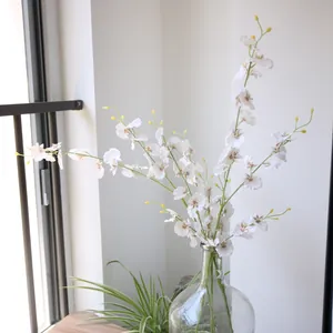 Detailed close-up shot of artificial white dancing orchid silk flowers in a glass vase