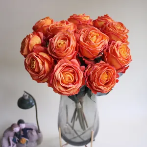 Detailansicht lebensechter orangefarbener Kunstrosen mit Brandrand in Vase