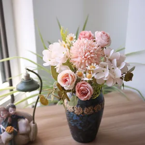 Detailansicht künstlicher Rosen und Chrysanthemen in einer eleganten blauen Vase