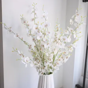 Detailed close-up of white silk dancing orchid branches in a ribbed ceramic vase