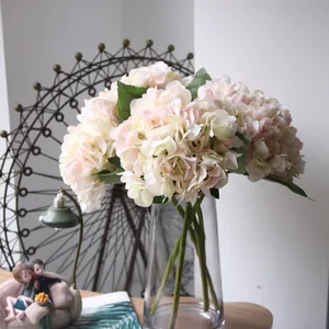 Close-up of elegant pink and cream artificial hydrangea bouquet in a clear glass vase