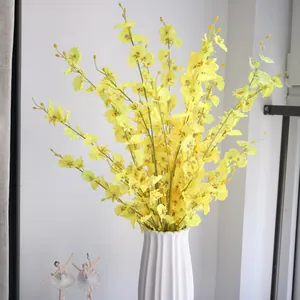 Close-up of vibrant yellow artificial dancing lady orchids with 5 branches in a white vase.