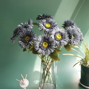 Detailed view of artificial gray African daisies in a elegant gold-rimmed glass vase