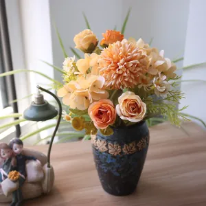 Künstlicher Herbststrauß aus Chrysanthemen und Rosen in einer strukturierten Vase