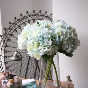 Detailed macro view of realistic light blue and white artificial hydrangea in a clear glass vase