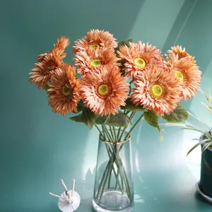 Macro shot of orange artificial gerbera flowers in a gold-rimmed glass vase