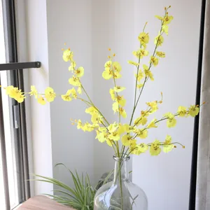 Detail of realistic yellow silk Oncidium dancing orchids arranged in a glass vase