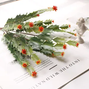 Detailed view of green artificial cactus plant with vibrant red flowers on white paper