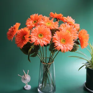 Close-up detail of vibrant orange artificial gerbera flowers in a clear glass vase