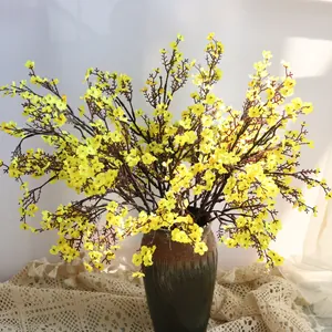 Detalle de flores de seda artificiales amarillas de paniculata en un jarrón de cerámica rústico