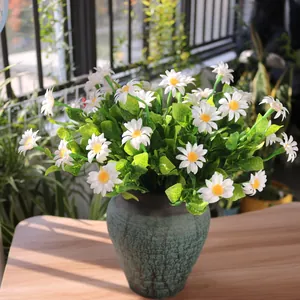 Close-up of artificial white daisies with yellow centers in a rustic ceramic vase